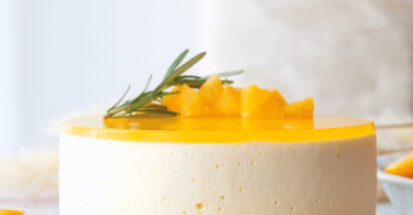 Gâteau au fromage sans cuisson avec une couche brillante de gelée d'orange, joliment présenté sur un plat de service.