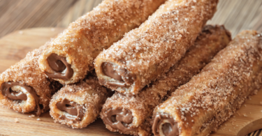 Roulés façon pain perdu garnis de pâte à tartiner, dorés et saupoudrés de sucre à la cannelle.