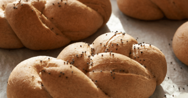 Mini brioches tressées dorées, moelleuses et délicatement dorées, servies sur une assiette.