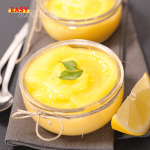 Crème dessert au citron dans un verre décoré de zestes de citron frais et d’un brin de menthe.