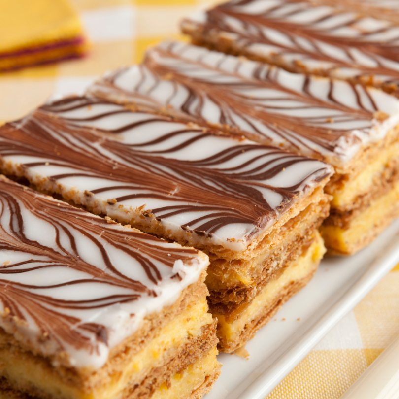 Mille-feuille maison, alternant couches de pâte feuilletée croustillante et crème pâtissière, décoré avec un glaçage classique au chocolat.