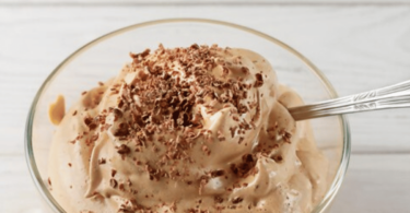 Mousse au café servie dans une verrine élégante, décorée de chocolat râpé et d’un biscuit croustillant.