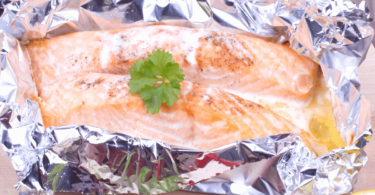 Poisson blanc en papillote avec des légumes et des herbes aromatiques dans une assiette