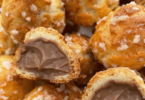 Chouquettes dorées et croustillantes, garnies de crème pâtissière au chocolat, posées sur une assiette élégante.