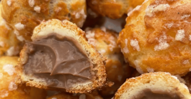 Chouquettes dorées et croustillantes, garnies de crème pâtissière au chocolat, posées sur une assiette élégante.