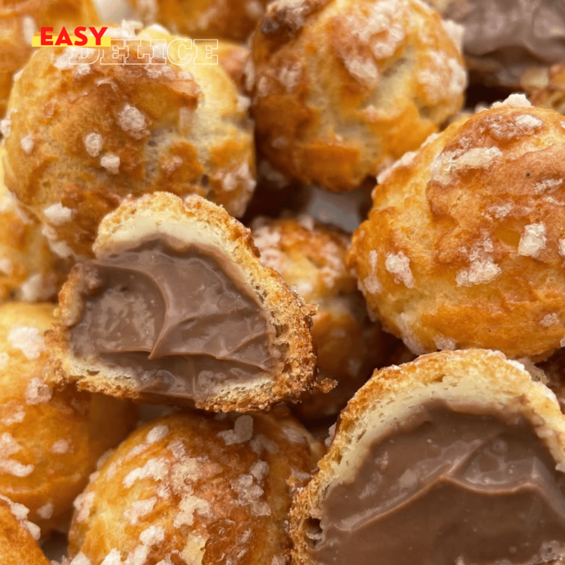 Chouquettes dorées et croustillantes, garnies de crème pâtissière au chocolat, posées sur une assiette élégante.