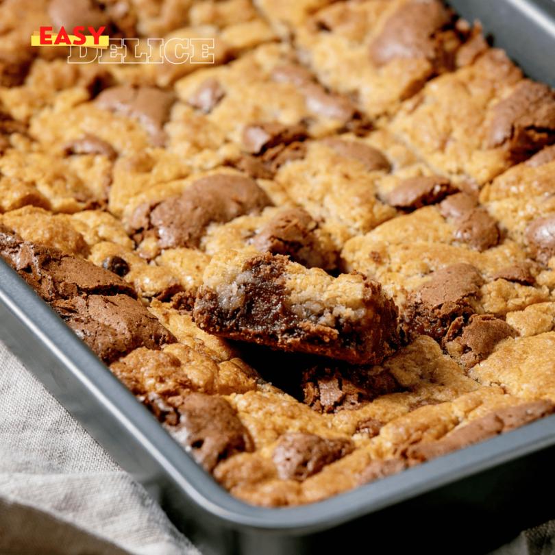 Cookie géant doré, garni de pépites de chocolat et nappé de pâte à tartiner, coupé en parts sur une planche en bois.