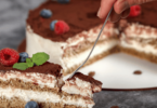 Gâteau tiramisu élégant avec une couche onctueuse de mascarpone, cacao premium saupoudré et présentation dans un cercle à entremet.