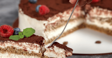 Gâteau tiramisu élégant avec une couche onctueuse de mascarpone, cacao premium saupoudré et présentation dans un cercle à entremet.