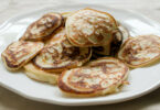 Une assiette de pancakes moelleux à base de banane et œufs, garnis de fruits frais et de miel