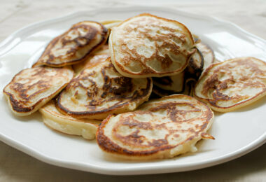 Une assiette de pancakes moelleux à base de banane et œufs, garnis de fruits frais et de miel