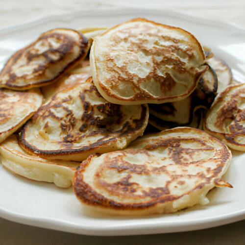 Une assiette de pancakes moelleux à base de banane et œufs, garnis de fruits frais et de miel