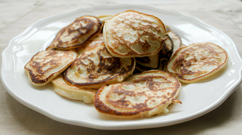 Une assiette de pancakes moelleux à base de banane et œufs, garnis de fruits frais et de miel