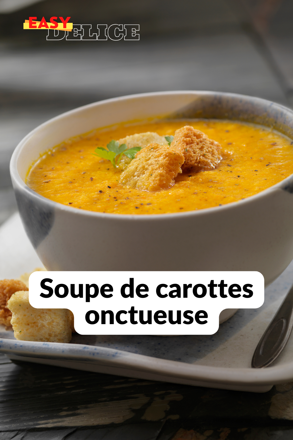 Bol de soupe de carottes onctueuse, garnie de crème fraîche et de quelques brins de coriandre.