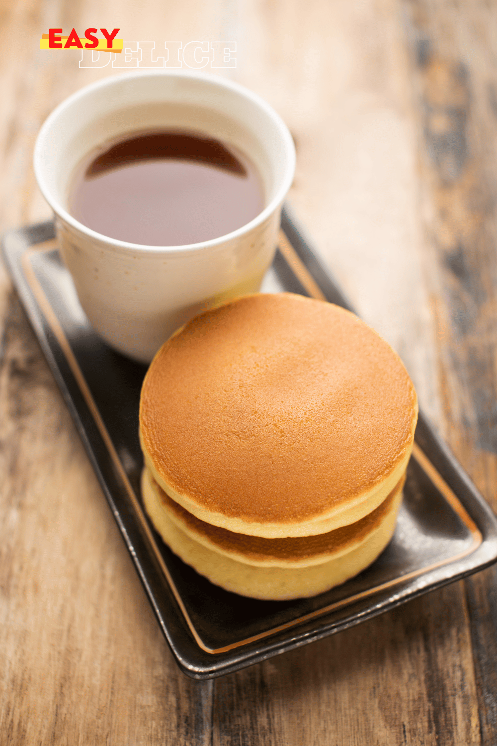 Pile de crêpes dorées façon McDonalds avec du beurre fondant et du sirop d'érable.

