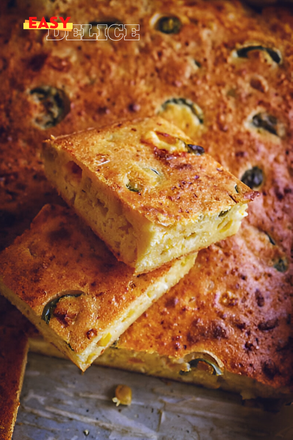  Tranche de pain de maïs mexicain doré, garnie de grains de maïs et de morceaux de jalapenos, avec une texture moelleuse.

