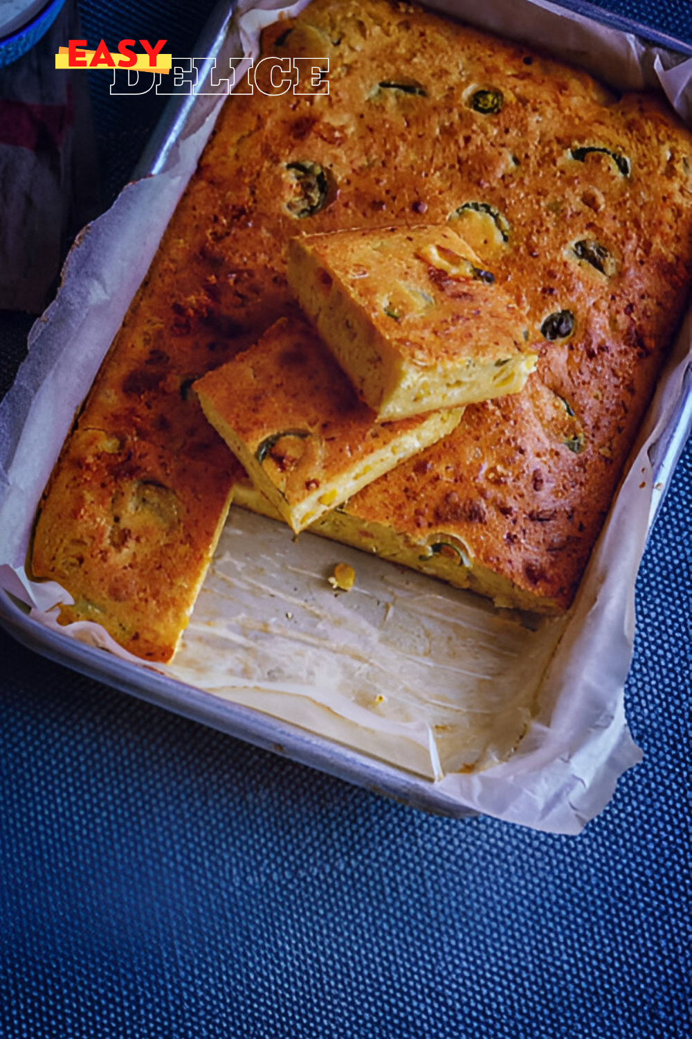  Tranche de pain de maïs mexicain doré, garnie de grains de maïs et de morceaux de jalapenos, avec une texture moelleuse.

