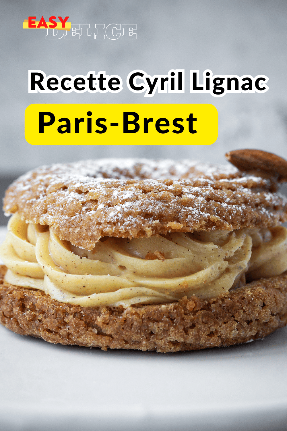 Paris-Brest gourmand avec une garniture de crème pralinée et une décoration d’amandes effilées et de sucre glace