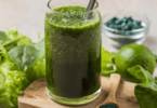 Verre de smoothie vert vibrant, garni de feuilles de menthe fraîche et tranches de citron