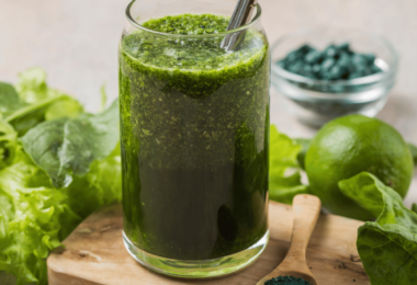 Verre de smoothie vert vibrant, garni de feuilles de menthe fraîche et tranches de citron