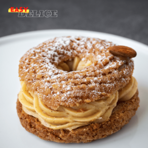 Paris-Brest gourmand avec une garniture de crème pralinée et une décoration d’amandes effilées et de sucre glace