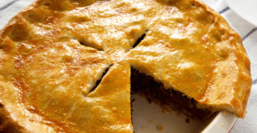 Une tourtière dorée et croustillante, servie avec une salade verte et une garniture de canneberges