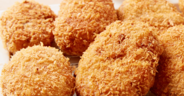 Assiette de croquettes de jambon dorées et croustillantes, accompagnée d'une sauce au yaourt.