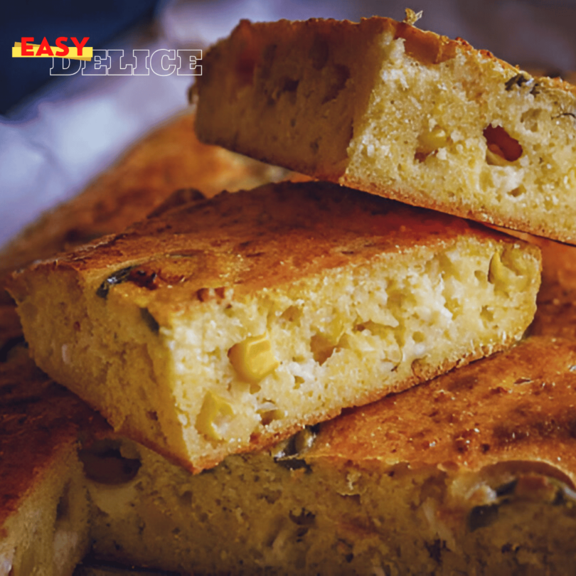 Tranche de pain de maïs mexicain doré, garnie de grains de maïs et de morceaux de jalapenos, avec une texture moelleuse.