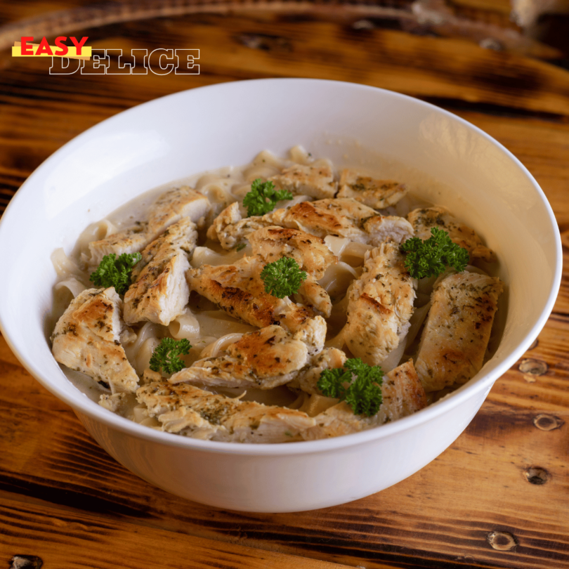 Pâtes crémeuses au poulet et au Boursin, garnies de persil frais, servies dans une assiette blanche.