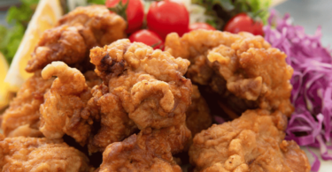 Poulet karaage croustillant doré cuit au Air Fryer, accompagné de quartiers de citron et d'une sauce japonaise.