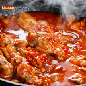 Plat de poulet mijoté à la sauce tomate, garni de basilic frais et servi avec du riz.