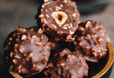 Ferrero Rocher faits maison, joliment dorés et garnis de noisettes concassées, prêts à être dégustés.