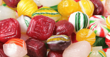 Des bonbons durs maison colorés, brillants, disposés sur une assiette, avec des arômes variés comme citron, fraise, et menthe.