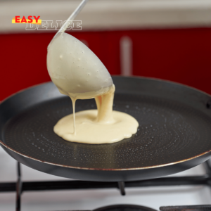 Pâte à crêpes lisse et onctueuse dans un bol, avec une louche prête à l'emploi pour des crêpes fines et dorées.