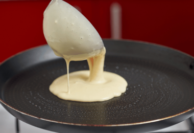 Pâte à crêpes lisse et onctueuse dans un bol, avec une louche prête à l'emploi pour des crêpes fines et dorées.