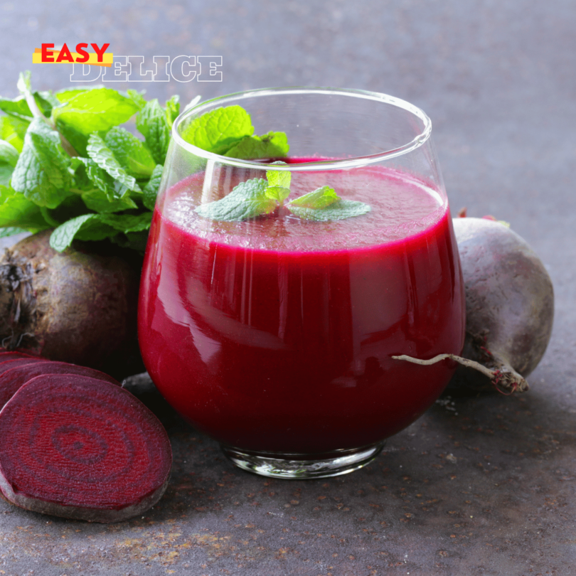 Un verre de jus de betteraves frais, accompagné de morceaux de betteraves crues et de rondelles de citron.