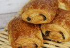 Petits pains au chocolat dorés et feuilletés sortant du four, posés sur une plaque