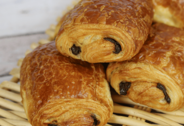 Petits pains au chocolat dorés et feuilletés sortant du four, posés sur une plaque