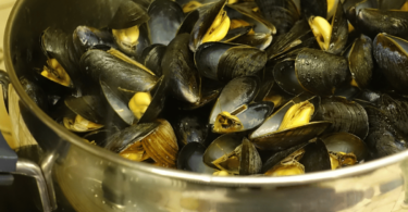 Une marmite de moules à la marinière, garnie de persil frais et servie avec du pain croquant