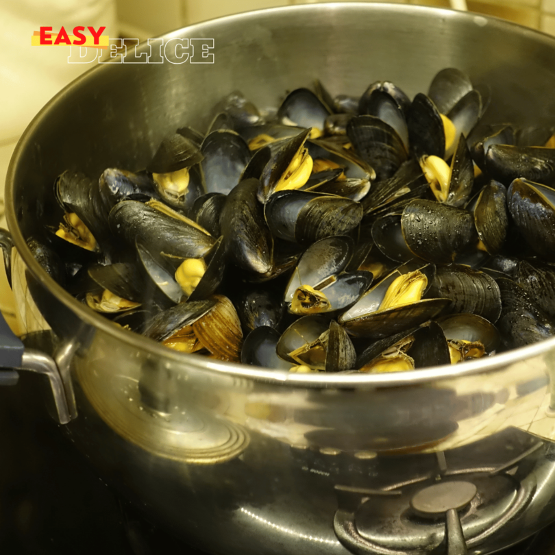 Une marmite de moules à la marinière, garnie de persil frais et servie avec du pain croquant