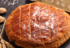 Galette des rois dorée et croustillante avec une part découpée révélant la garniture d’amande