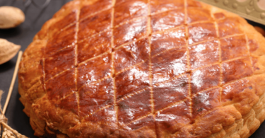 Galette des rois dorée et croustillante avec une part découpée révélant la garniture d’amande