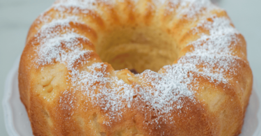 Un Bundt cake au citron doré et moelleux, joliment glacé, posé sur un plat élégant