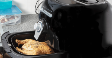 Airfryer moderne sur un comptoir de cuisine, entouré de légumes frais et de mets cuisinés