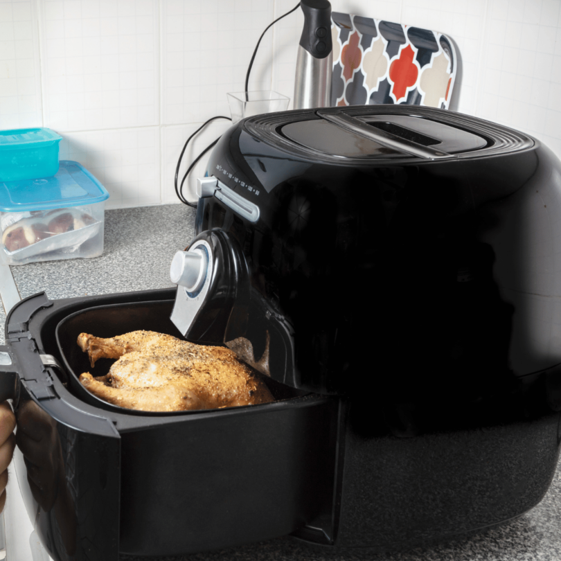 Airfryer moderne sur un comptoir de cuisine, entouré de légumes frais et de mets cuisinés