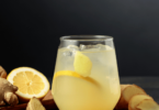 Une boisson detox au citron et gingembre servie dans un verre avec des rondelles de citron et des morceaux de gingembre