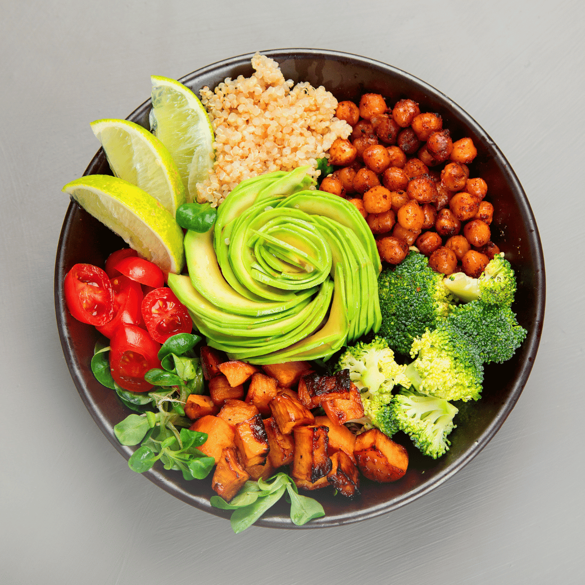 Assiette colorée de plats végétaliens : légumes rôtis, riz aux herbes, tofu mariné et avocat.