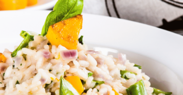 Bol de risotto à la courge butternut garni de parmesan râpé et de feuilles de sauge fraîche.