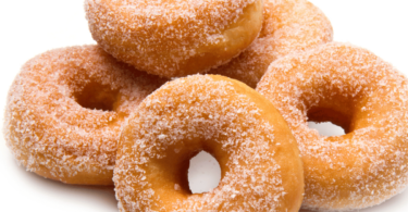 Beignets moelleux dorés et saupoudrés de sucre, servis sur une assiette.