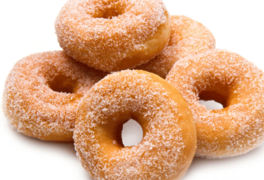 Beignets moelleux dorés et saupoudrés de sucre, servis sur une assiette.